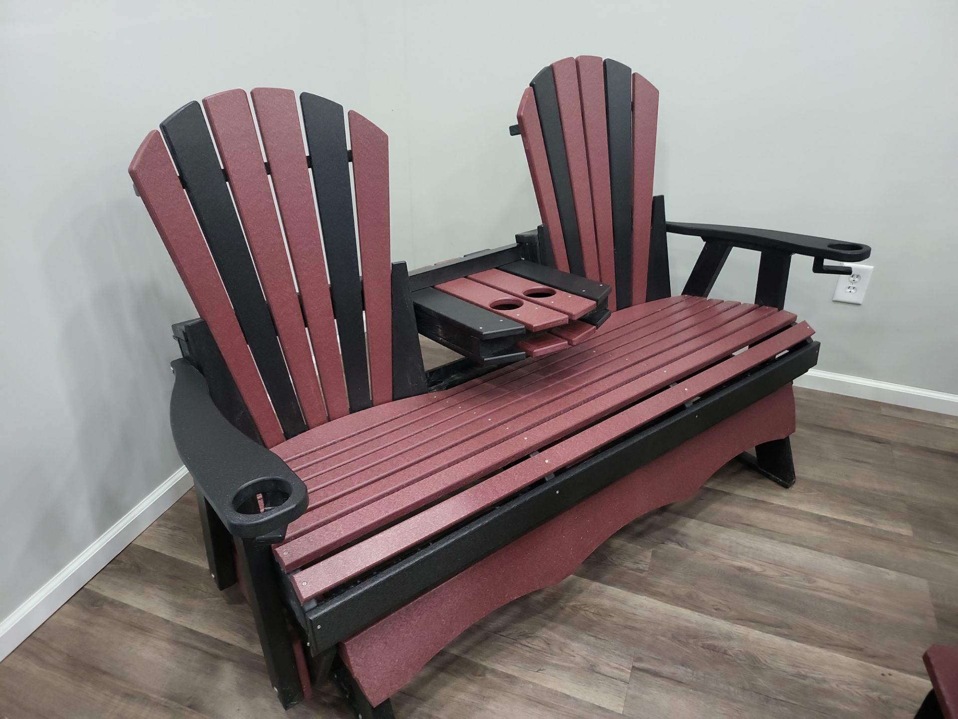 A red and black lawn chair is sitting on a wooden floor in a room.