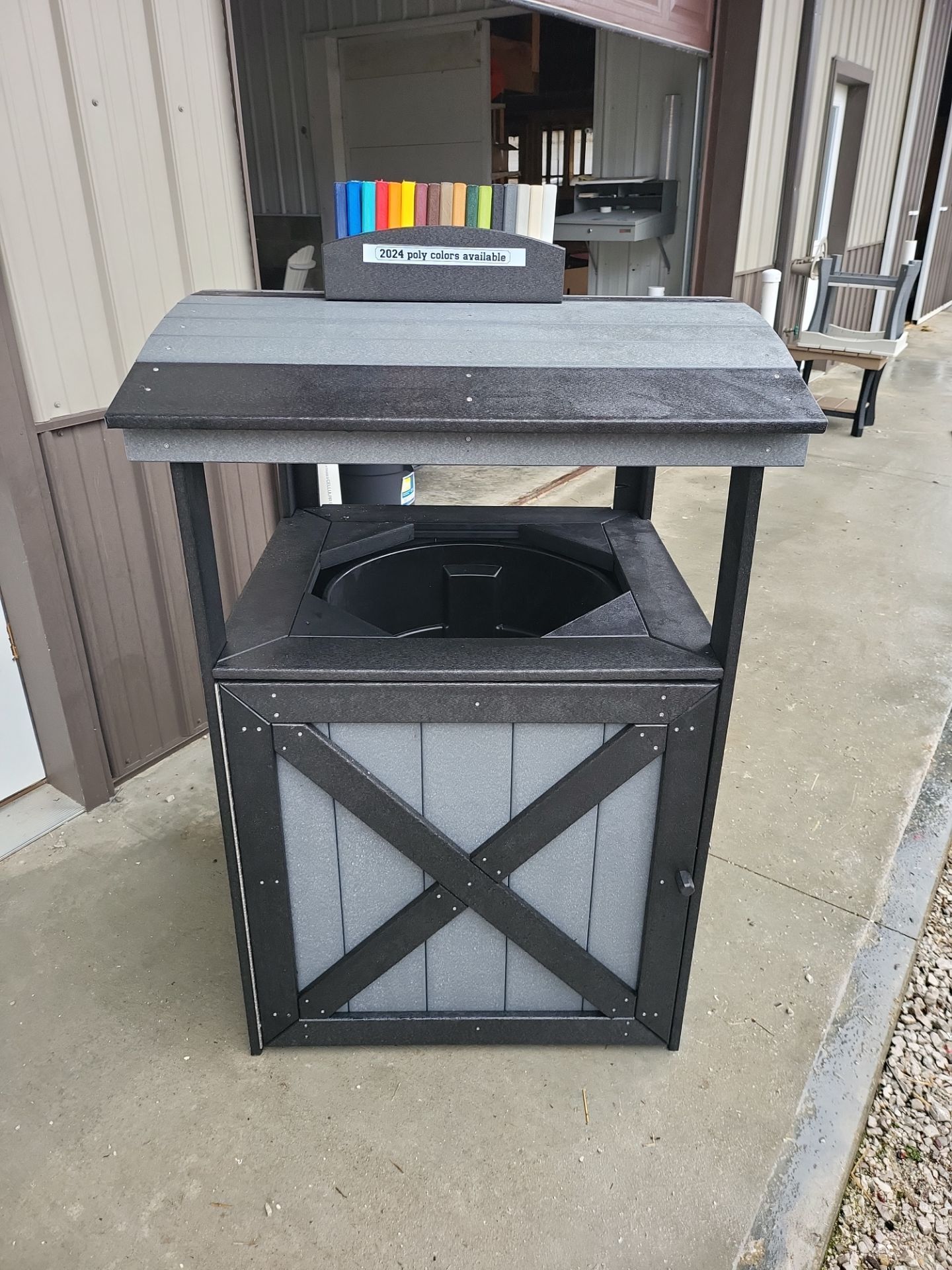 A trash can is sitting on the sidewalk in front of a building.