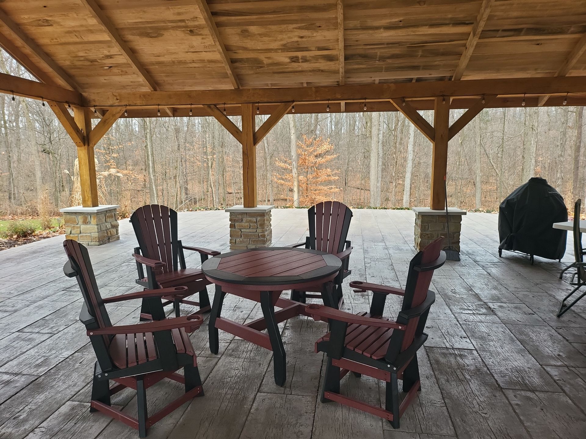 A patio with a table and chairs under a wooden roof.
