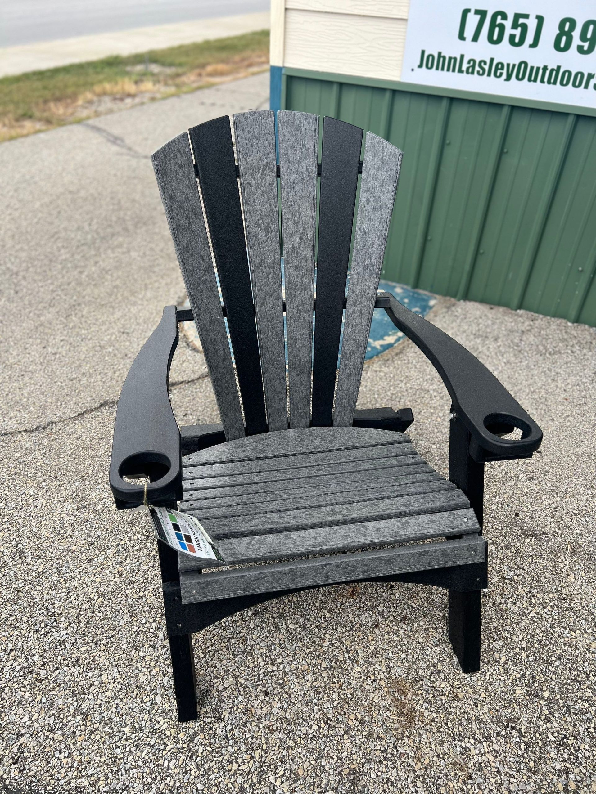 A gray and black adirondack chair is sitting on gravel