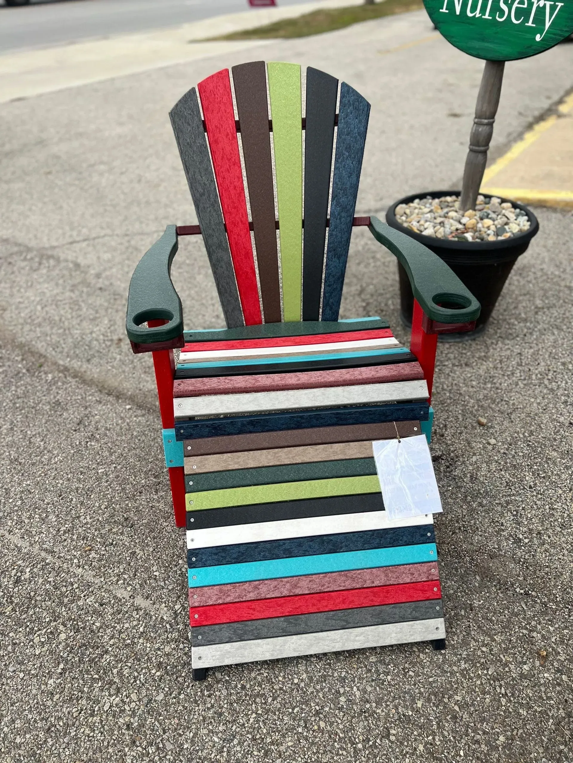 A colorful chair is sitting on the side of the road next to a potted plant.
