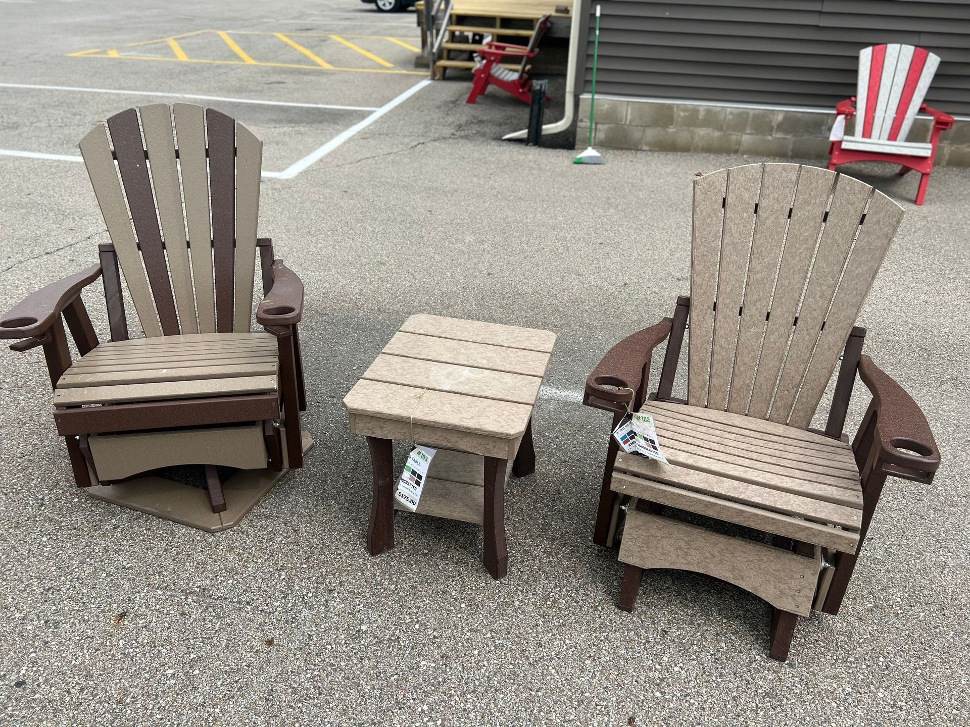 Three wooden chairs and a table are sitting in a parking lot.