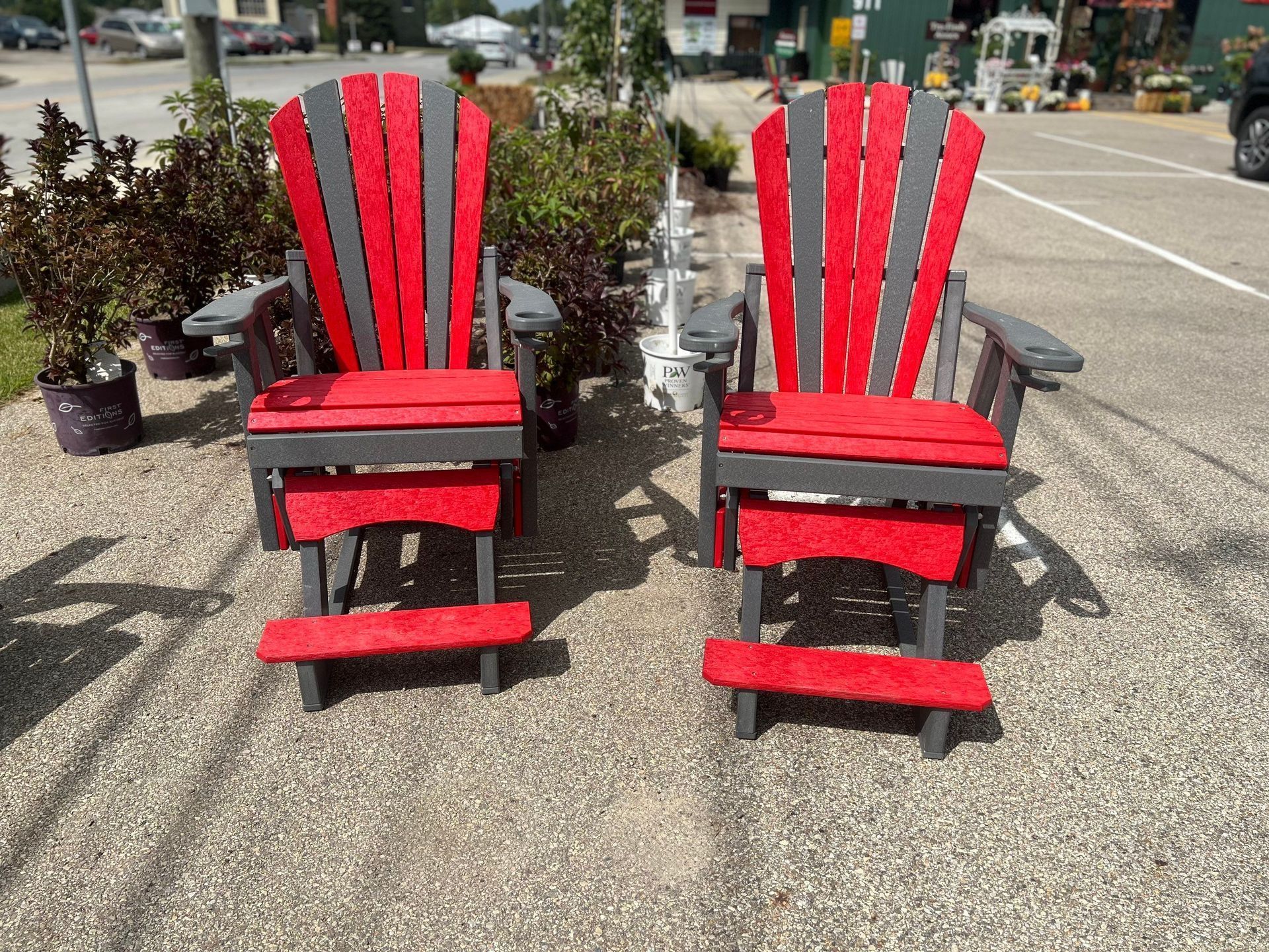 Two red and gray adirondack chairs are sitting in a parking lot.