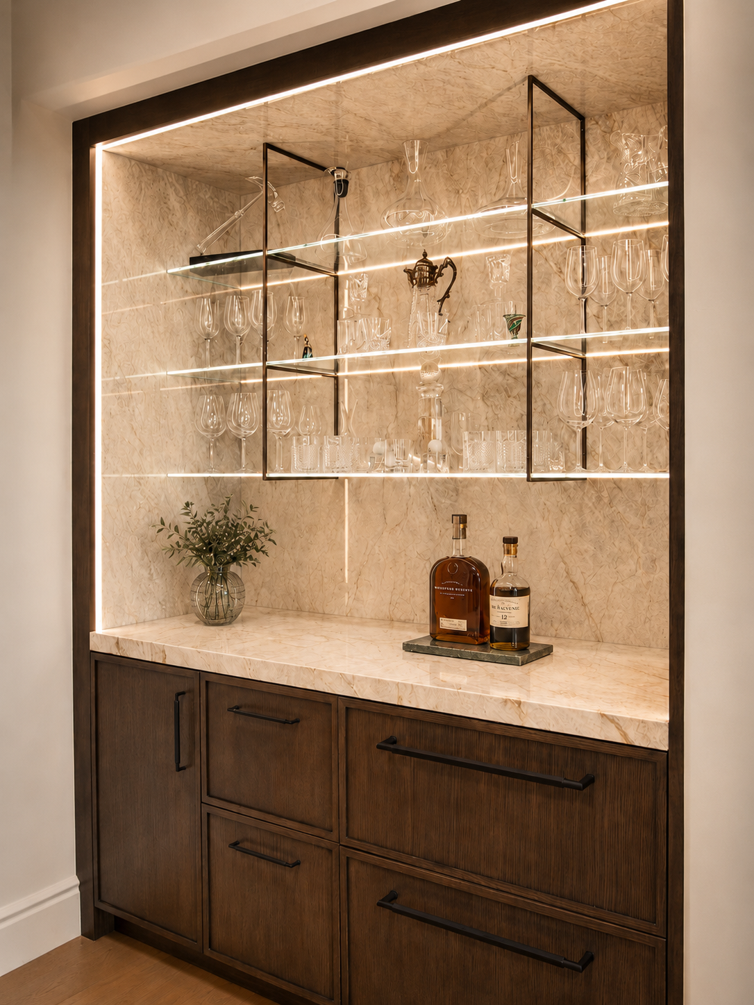 Built-in backlit bar cabinet with glass shelves, wood base cabinets, and countertop decor