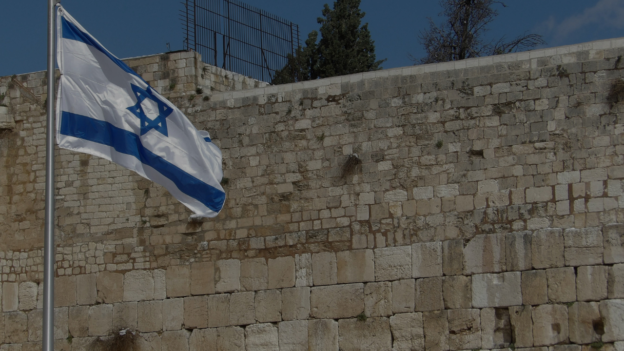 Israeli flag displayed along the ancient walls of Jerusalem’s Old City in the afternoon light