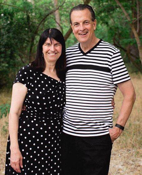 Pastor Bob and Roxanne Fetterhoff smiling together in a wooded outdoor setting