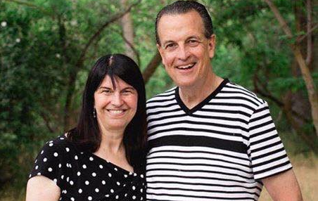 Pastor Bob and Roxanne Fetterhoff smiling together in a wooded outdoor setting