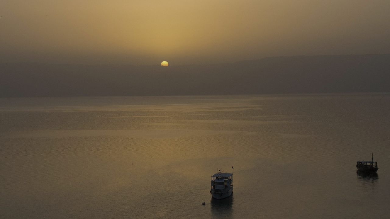 Two fishing boats on the calm waters of the Sea of Galilee at sundown