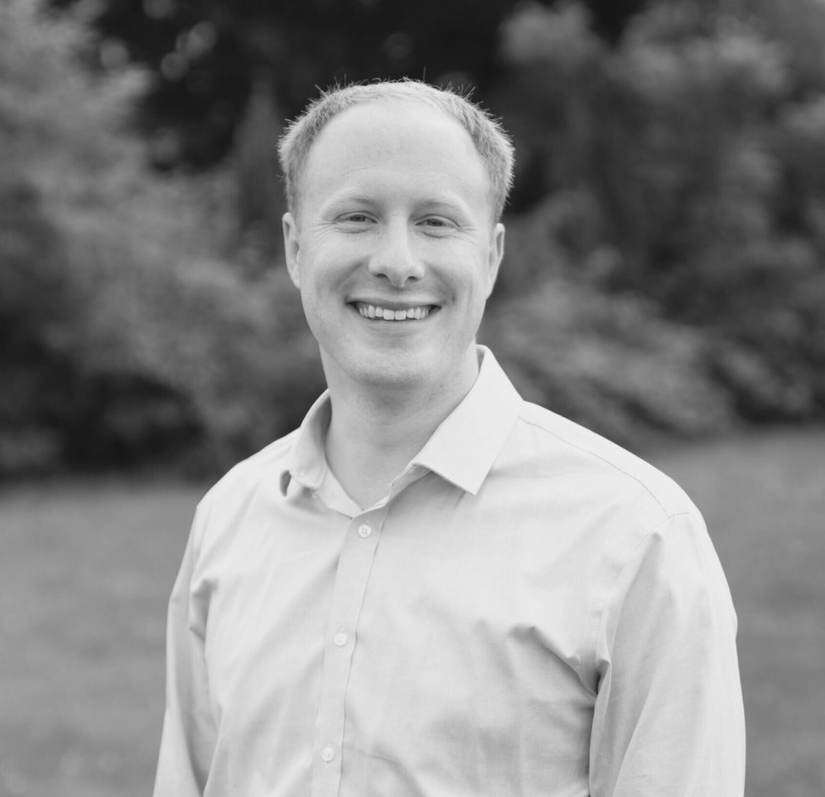 Black-and-white profile portrait of Pastor Adam Swift smiling at the camera