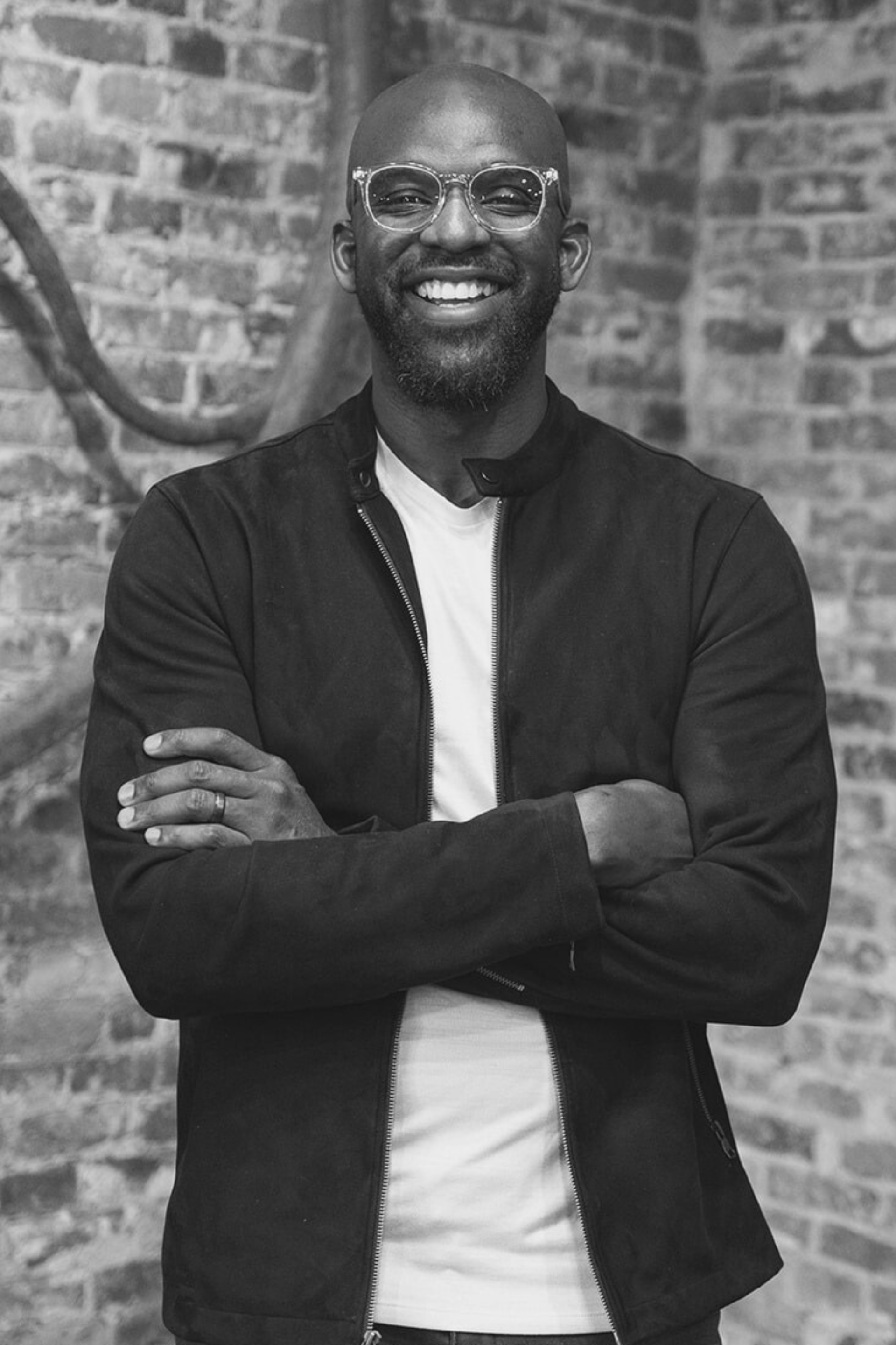 Black-and-white headshot of Dan Owolabi, CEO of Branches Worldwide and Owolabi Leadership, smiling at the camera