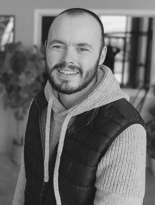 Black-and-white profile portait of Pastor Jared Gudeman smiling at the camera