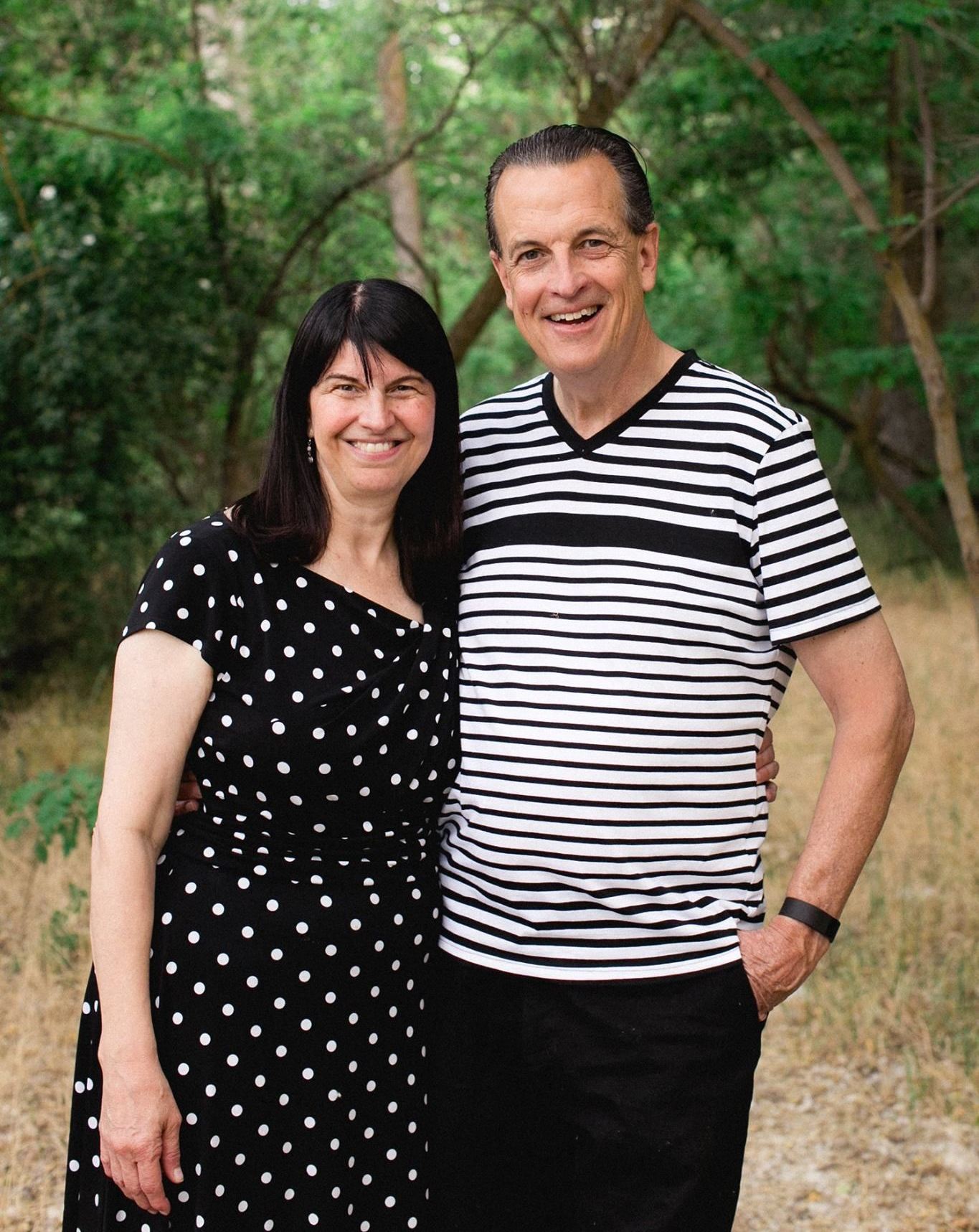 Pastor Bob and Roxanne Fetterhoff smiling together in a wooded outdoor setting
