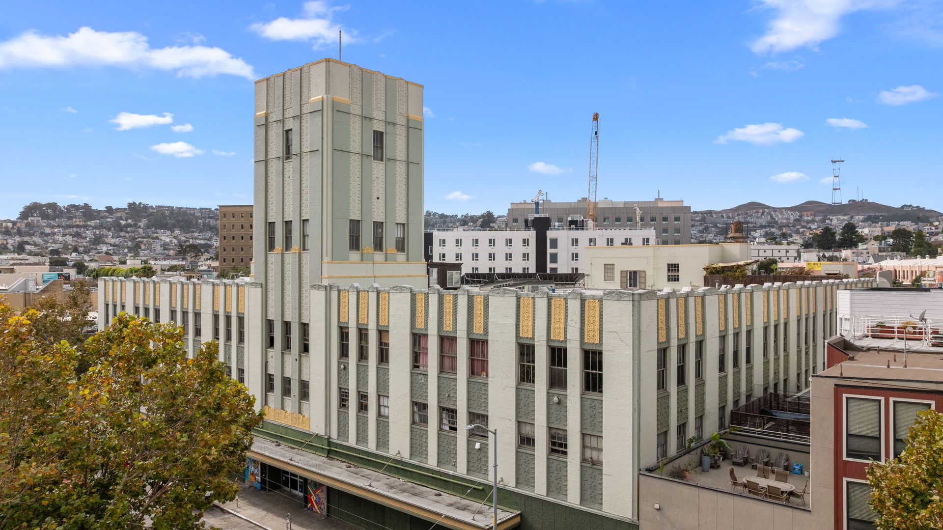 Gray art deco building with a tower, cars parked on the street in front.