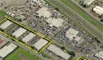 Aerial view of commercial buildings, parking lots, and a highway.