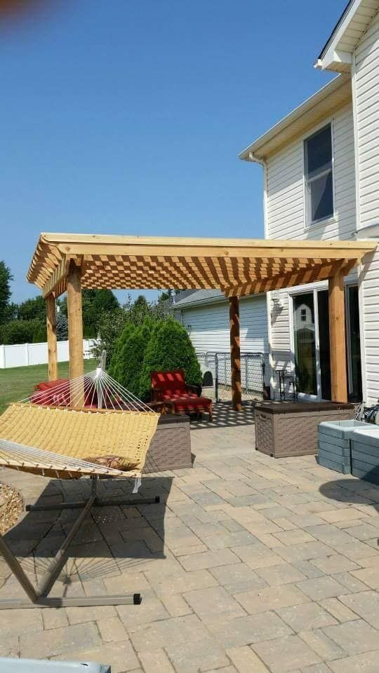Backyard patio with a wooden pergola, outdoor chairs, and a house exterior on the right