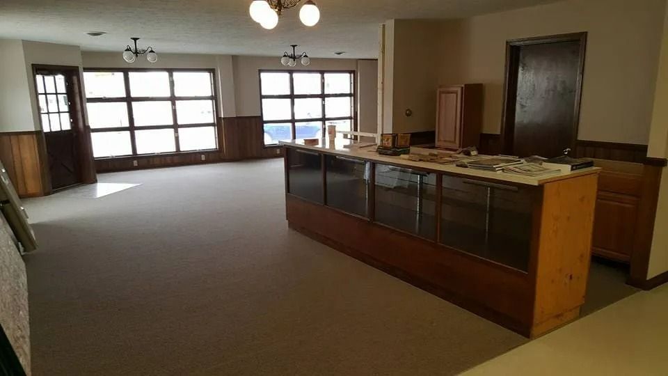 Empty office lobby with carpeted floor, wood counter, and large windows