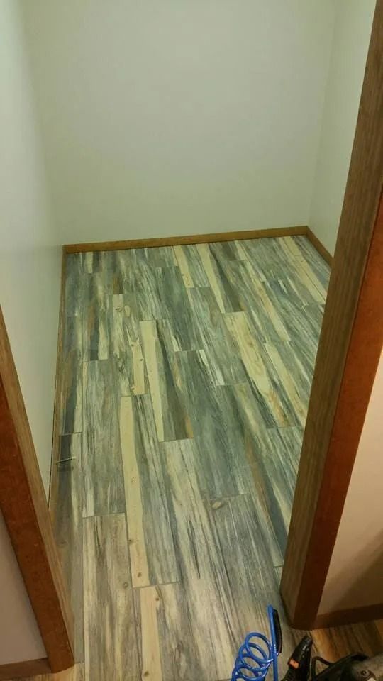 Small empty room with wood trim and greenish patterned flooring, viewed through a doorway.