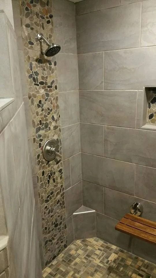 Tile shower stall with mosaic accent strip, chrome fixtures, and a built-in wooden bench.