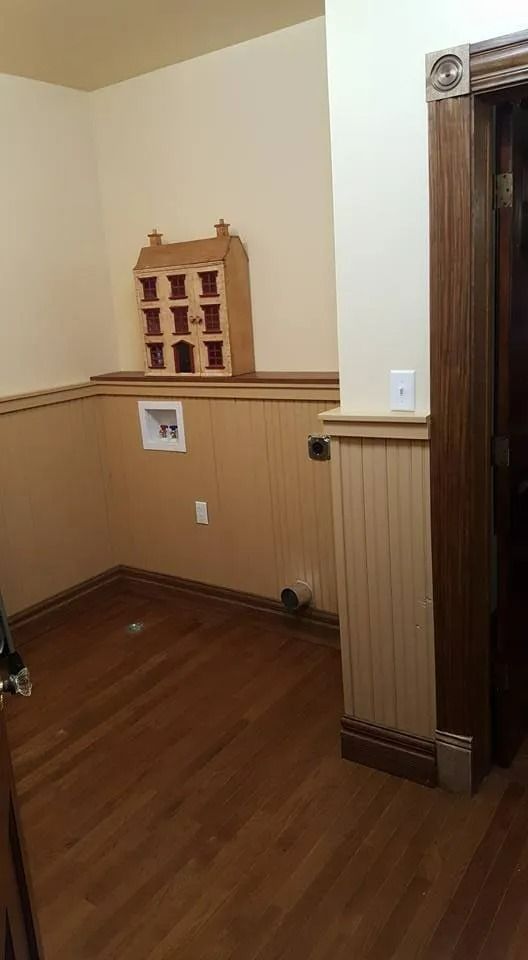 Empty room with wood floor, beige walls, and a doorway on the right.