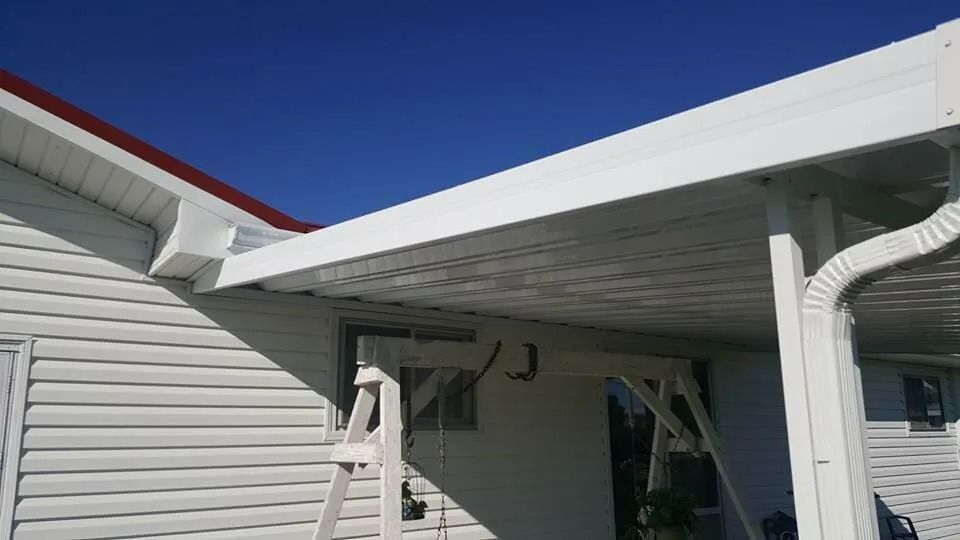 White house eaves and gutter with a downspout under a bright blue sky