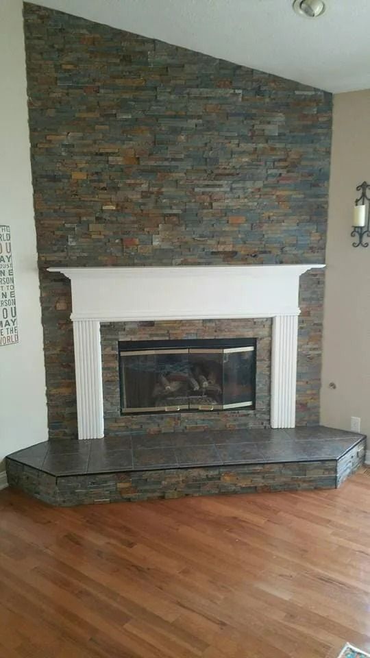 Stone fireplace with white mantel and dark hearth in a room with hardwood floors.