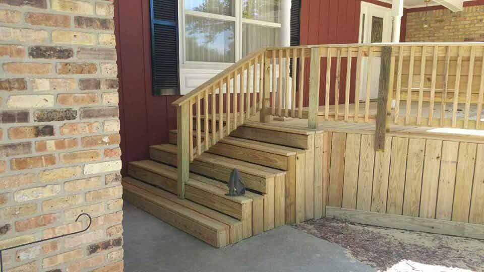 Wooden wheelchair-access ramp beside brick house steps and porch railing