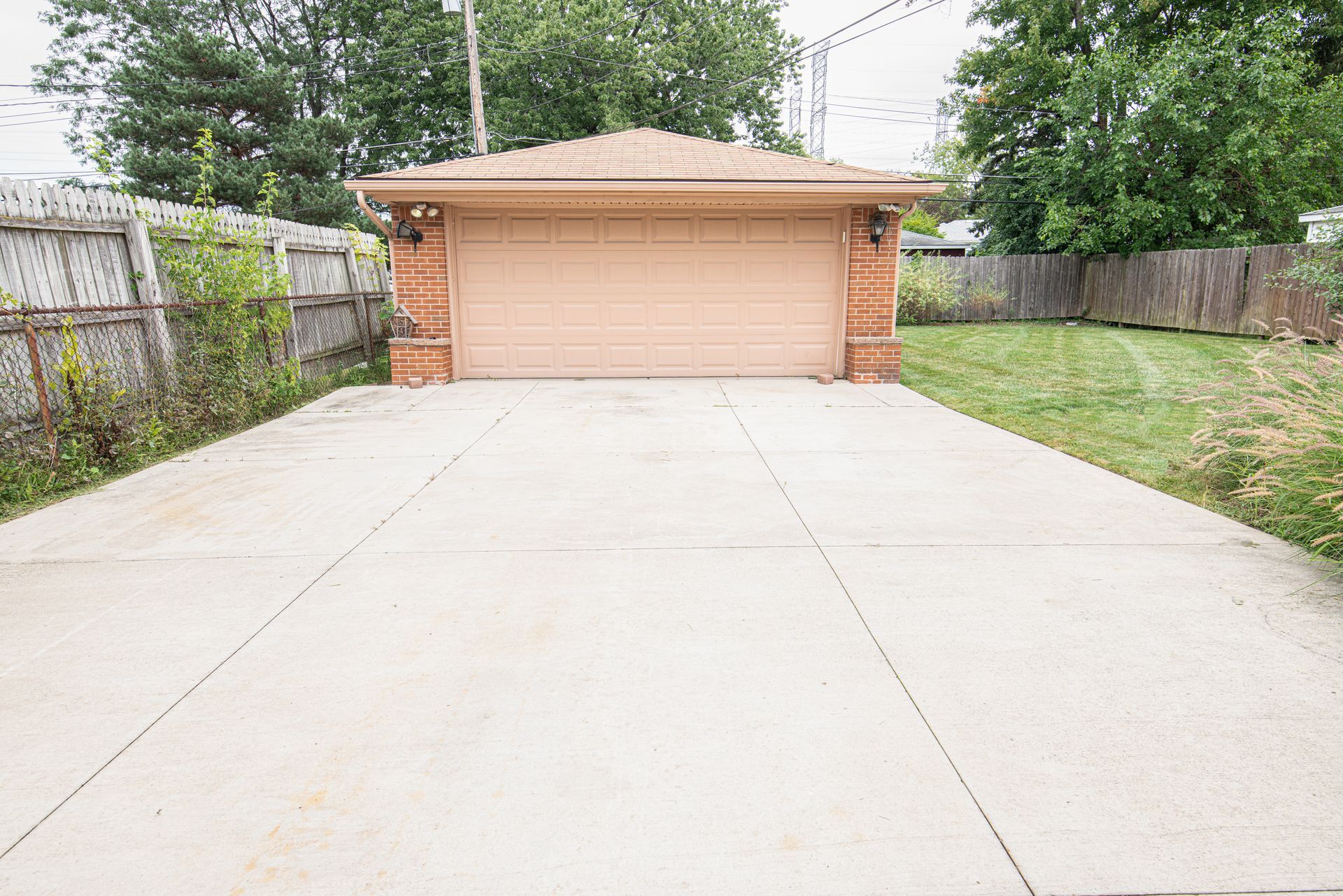 Wide concrete driveway leading to a peach two-car garage with a grassy yard on the right.