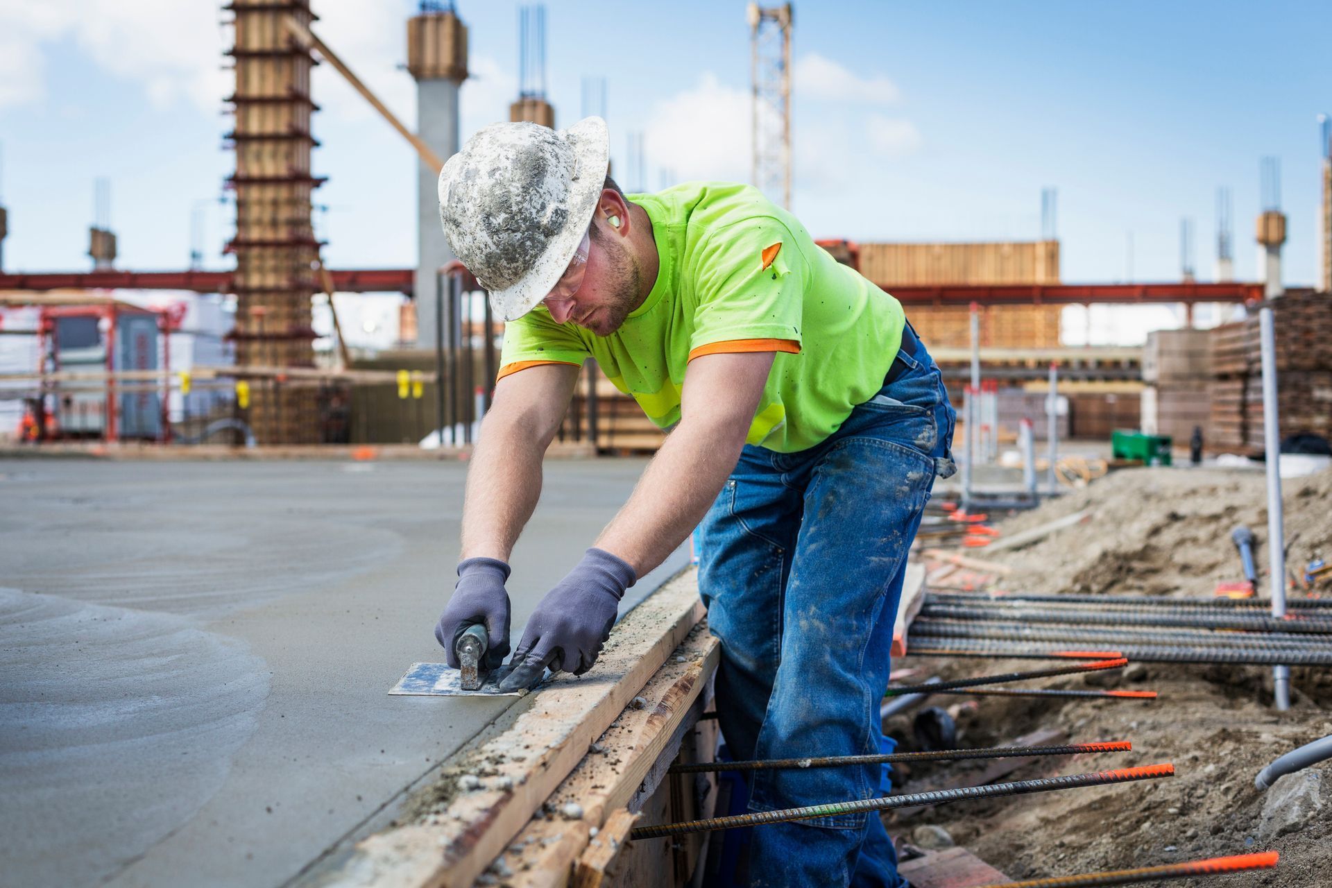 Construction worker smoothing wet concrete with a trowel at a construction site.