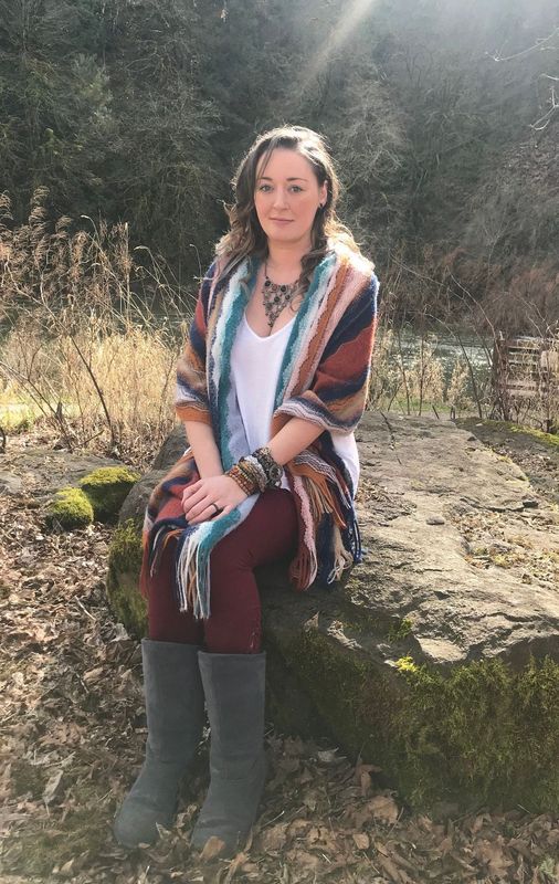 A woman is sitting on a rock in the woods.