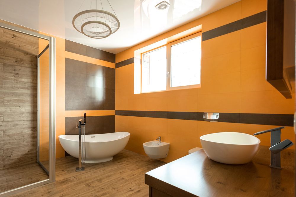 Bagno moderno con vasca freestanding, pareti arancioni, ampia finestra e doppio lavabo.