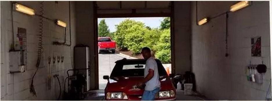 A man standing next to a red car in a garage