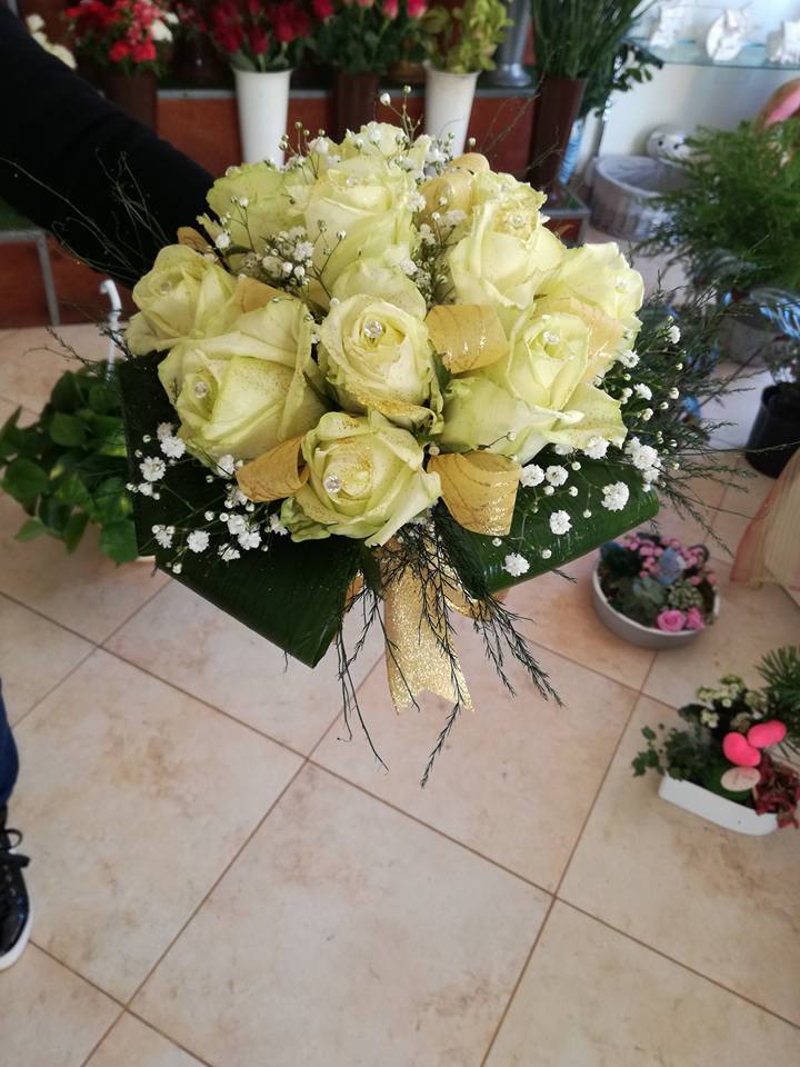 Bouquet di rose giallo chiaro con gypsophila, disposte a forma quadrata e tenute in mano da una persona.