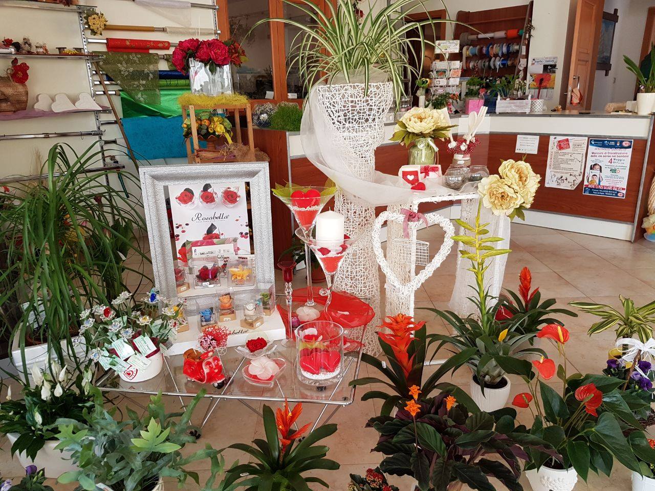 Esposizione di fiori con varie piante e decorazioni in rosso e bianco.