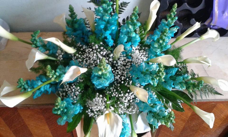 Composizione floreale con fiori turchesi, calle bianche e gypsophila.