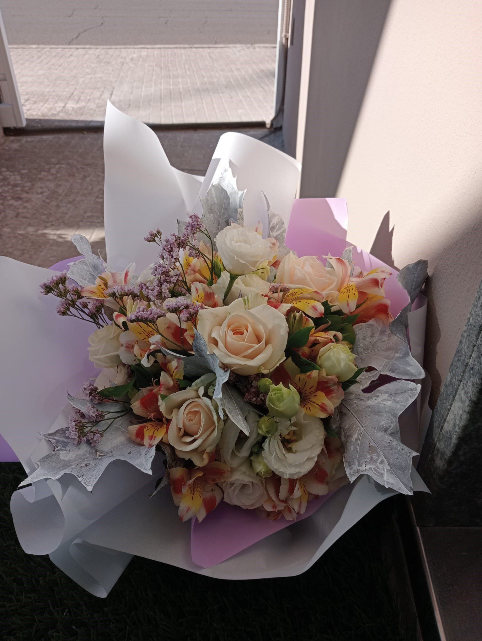 Bouquet di fiori color crema, pesca e gialli in carta bianca e viola.