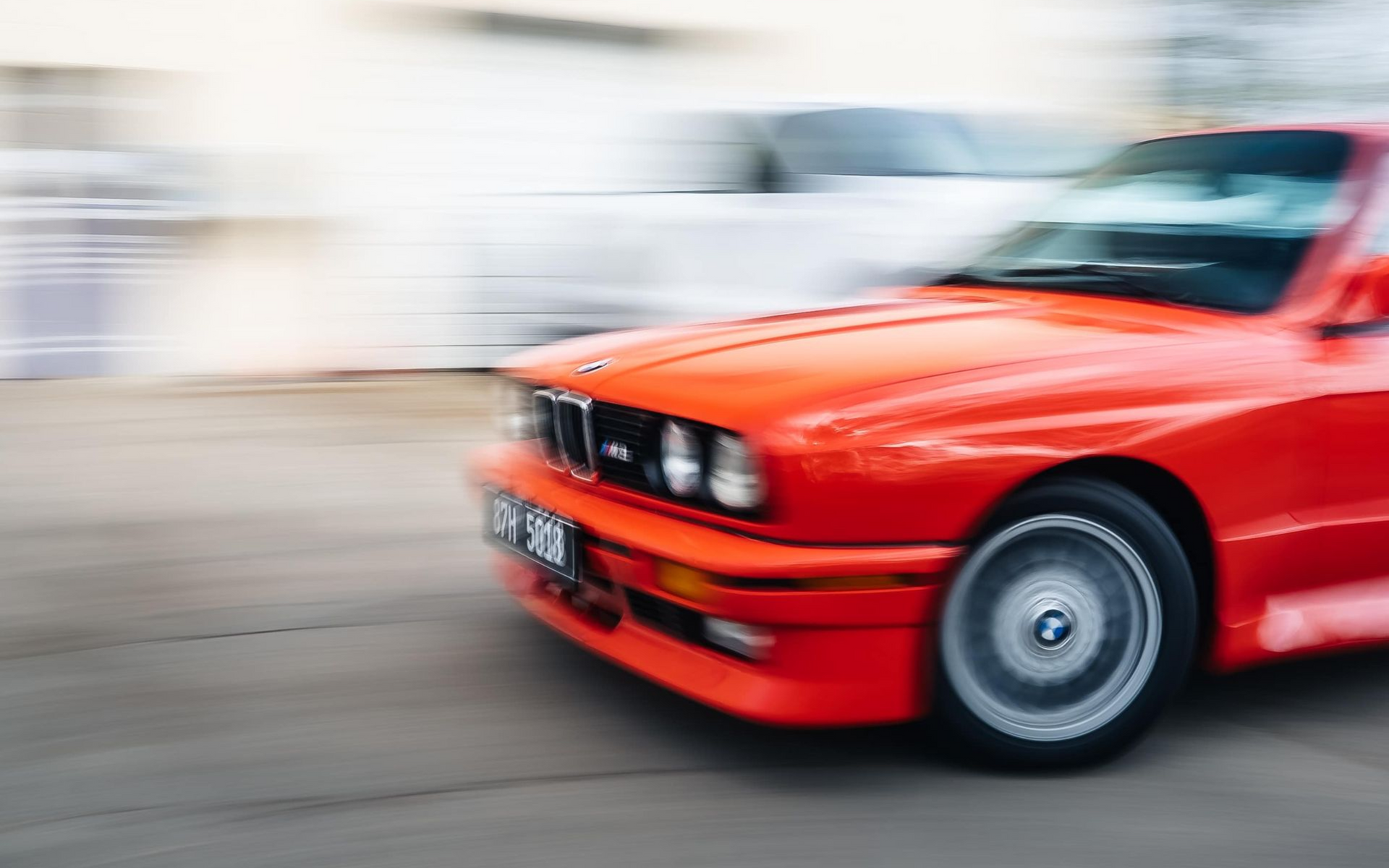 Red BMW car with blurred background, in motion.
