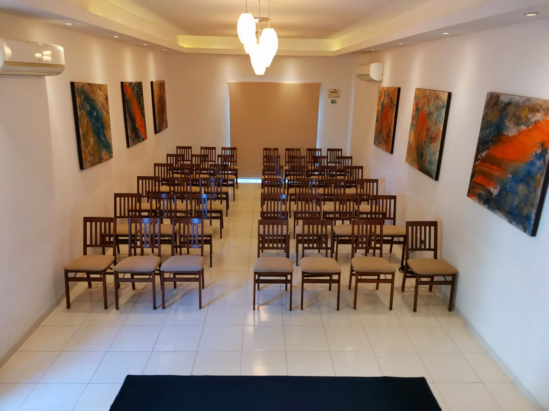 Una habitación con filas de sillas y cuadros en la pared.