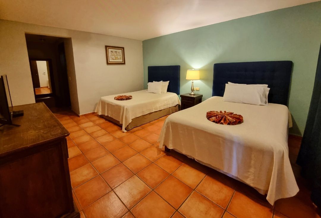 Una habitación de hotel con dos camas, una cómoda y una televisión.