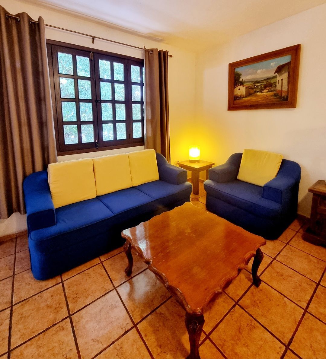 Una sala de estar con un sofá azul y almohadas amarillas.