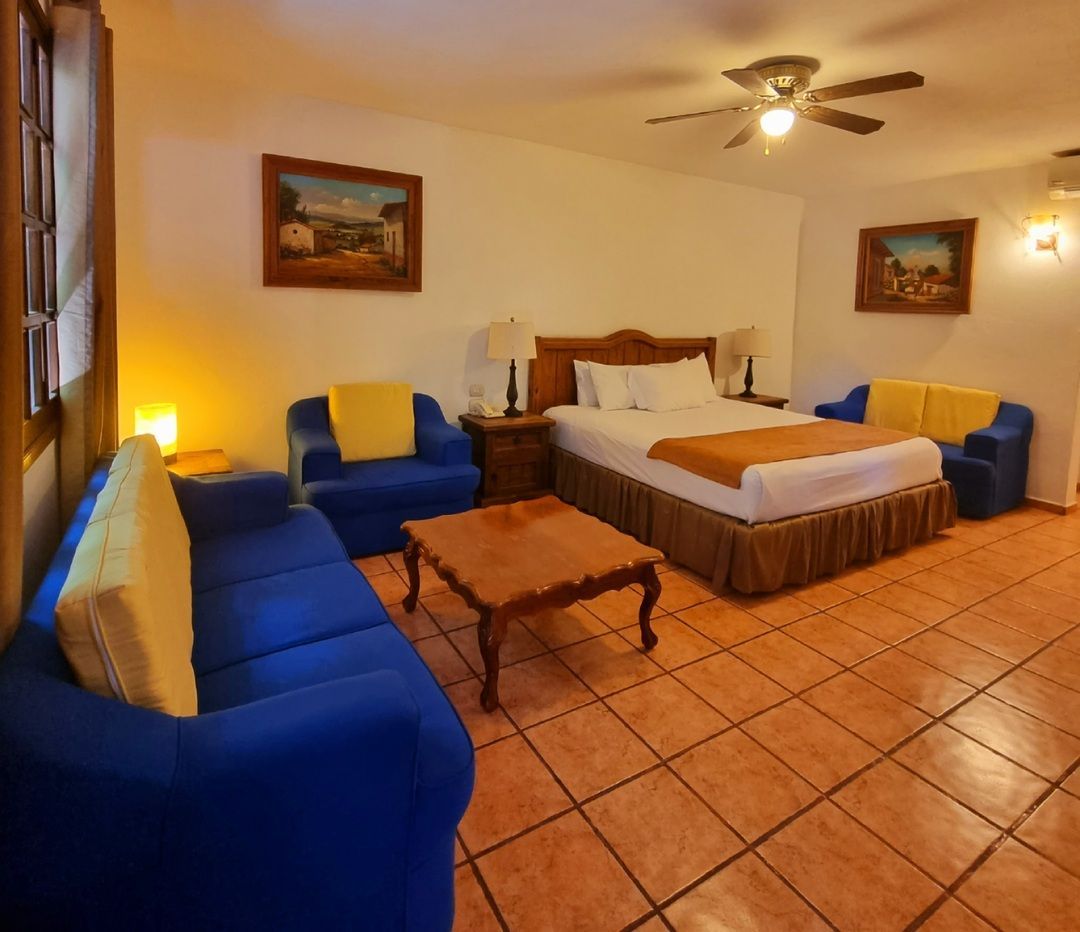 Una habitación de hotel con una cama grande y un ventilador de techo.