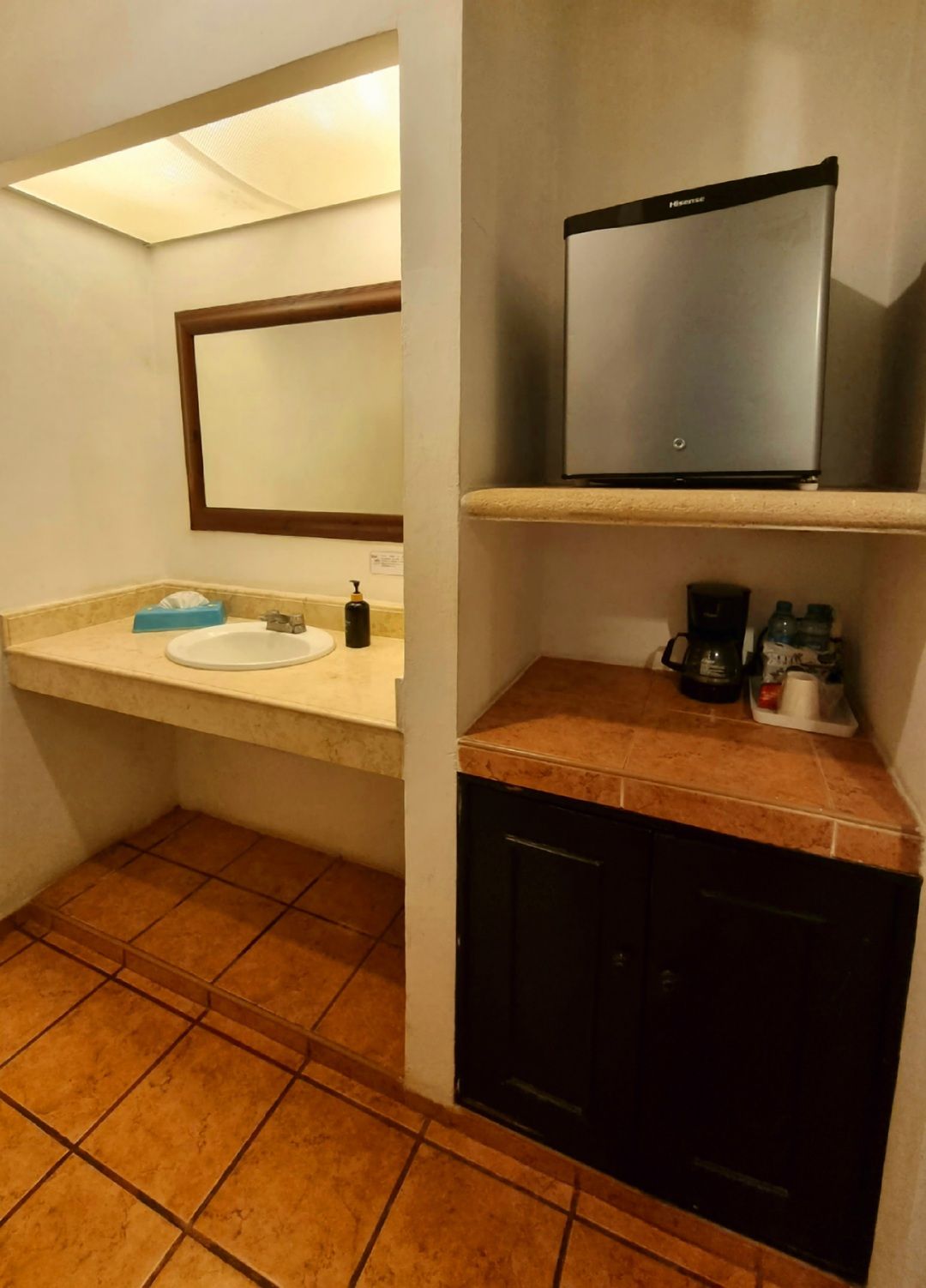 Un baño con lavabo y una pequeña nevera.
