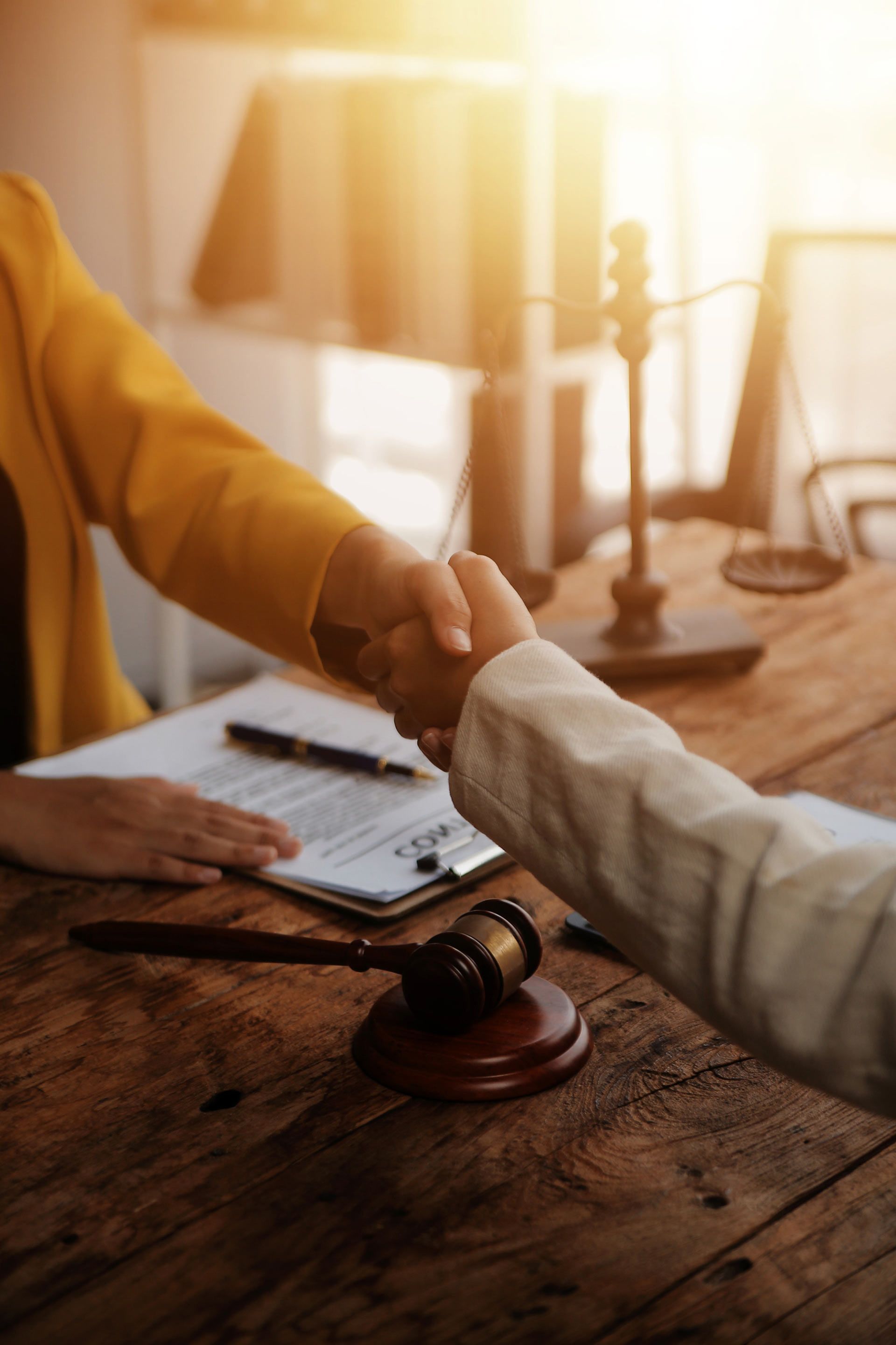 A woman is shaking hands with a judge while sitting at a wooden table.