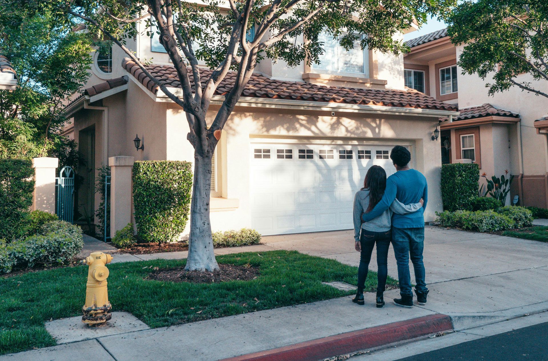 Couple gardening together, talking. House with porch in background.