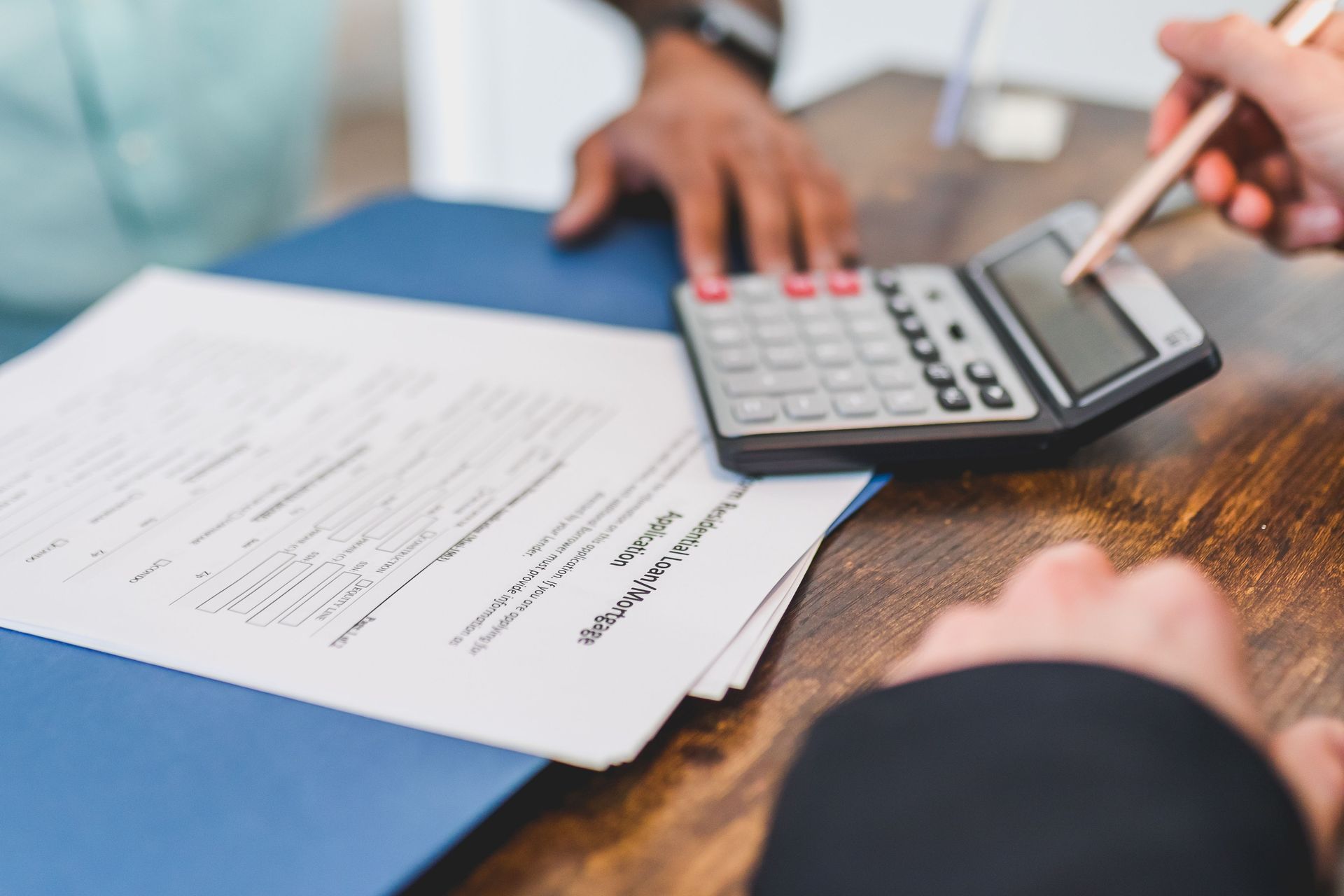 Person reviewing documents at a table in a bright office, holding a printed report.