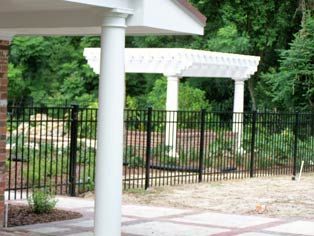 A white pergola is surrounded by a black fence