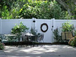 A white fence surrounds a patio area with tables and chairs.