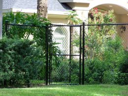 A chain link fence with a gate in front of a house