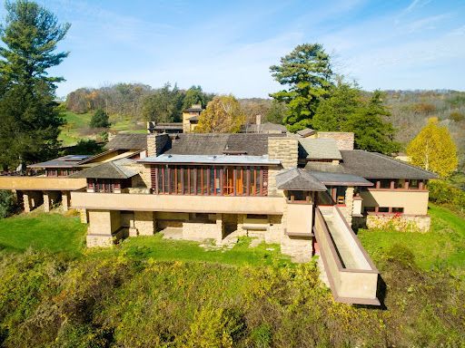 Frank Lloyd Wright's Fallingwater house, a sprawling beige and brown structure built into a hillside with surrounding trees.
