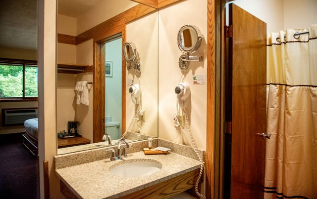 Bathroom with mirror over vanity, sink, and hairdryer. Toilet, door, and shower curtain visible.