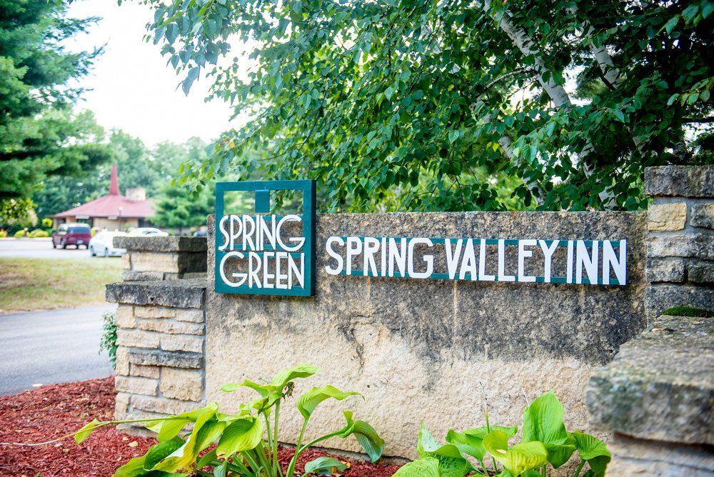 Sign for Spring Green Spring Valley Inn, green and white text on a stone structure.